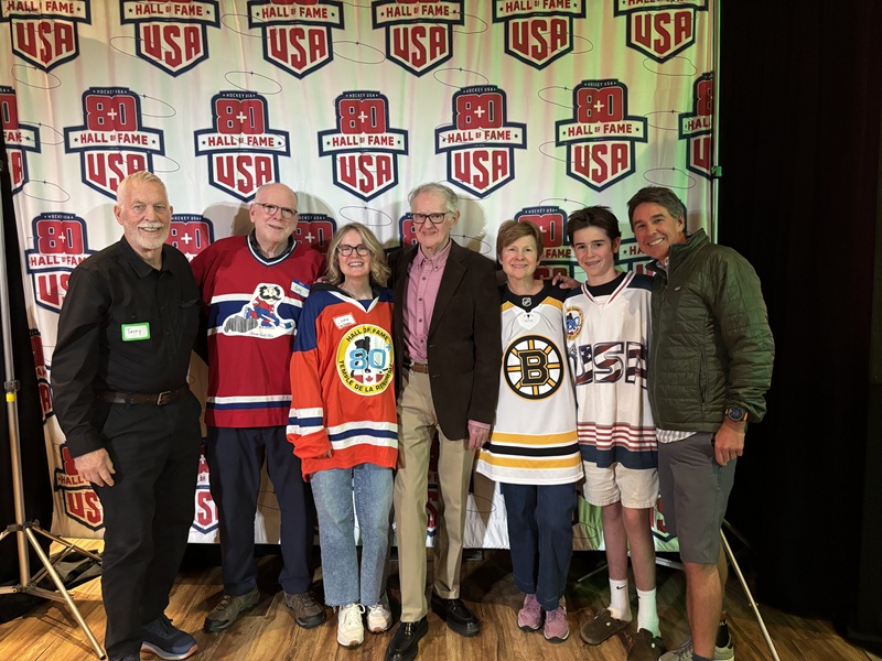 Fred Merchant with his family in front of the USA 80+ Hockey Hall of Fame step-and-repeat banner