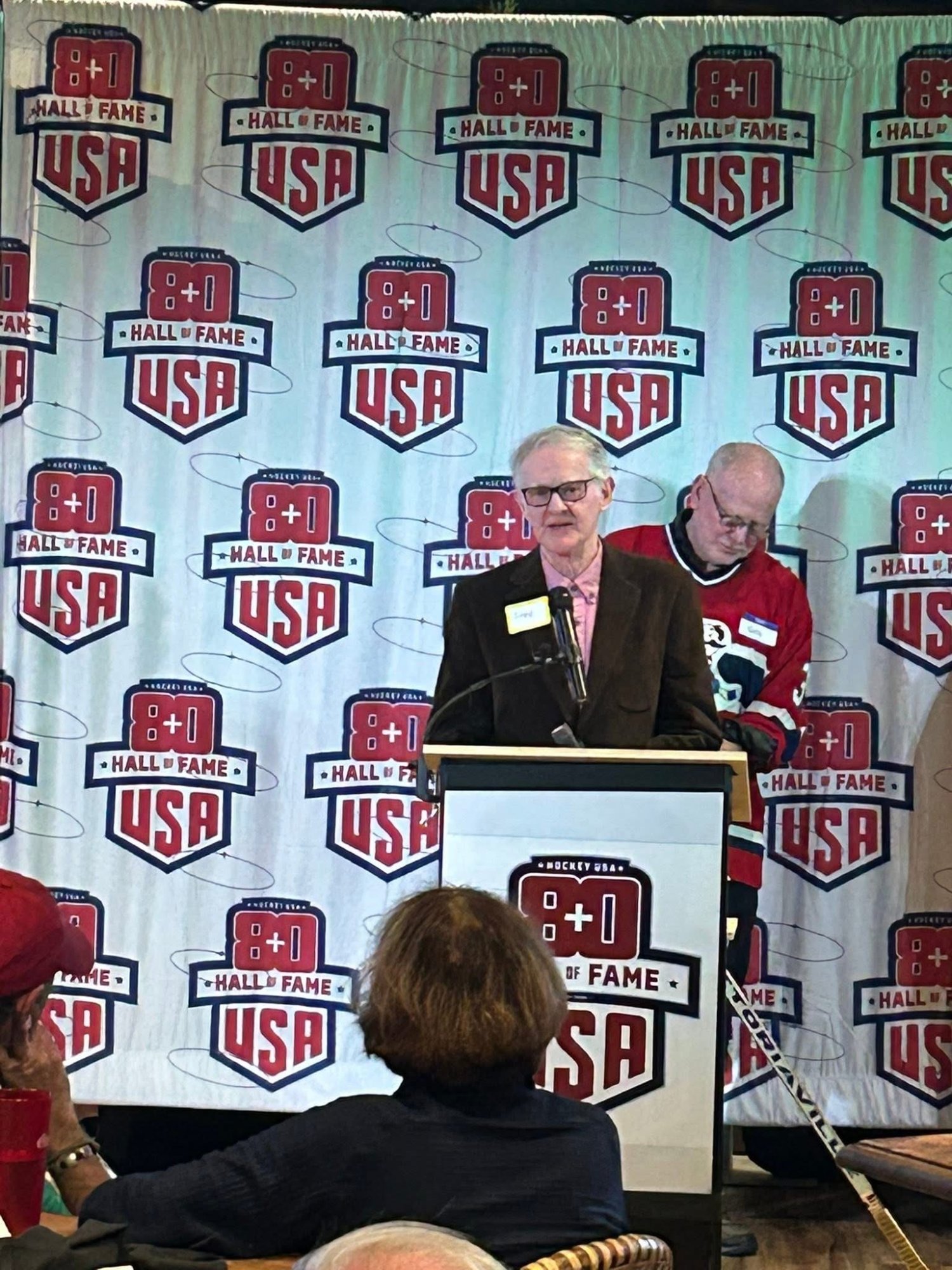 Fred Merchant speaking at the podium during the 2025 Induction Ceremony