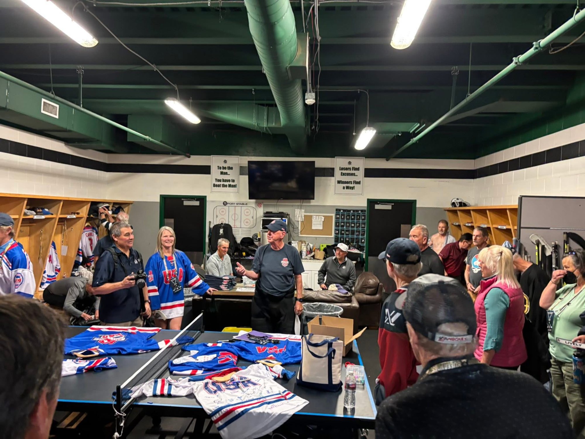 Inductees and volunteers gathering in the locker room at Blue Sport Stable before the Legends Game